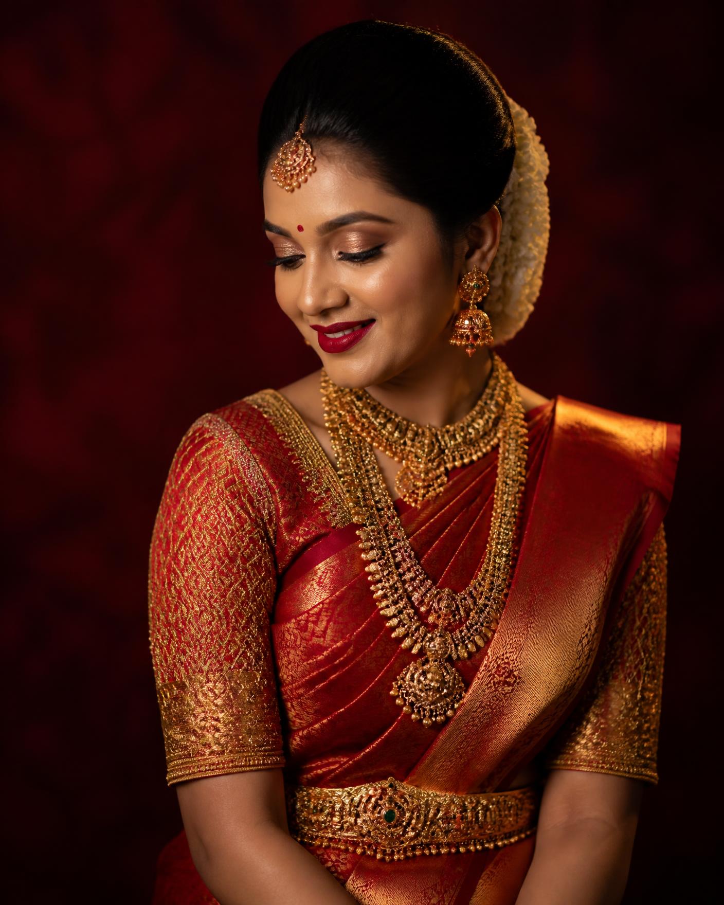 Bride in a red and gold silk saree with traditional South Indian bridal makeup